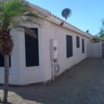Single-story house with white walls and a palm tree in the yard.